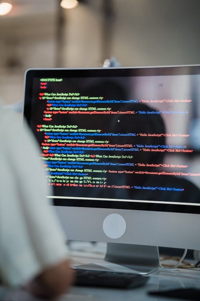 A close-up of a computer screen displaying colorful coding script in an office environment.